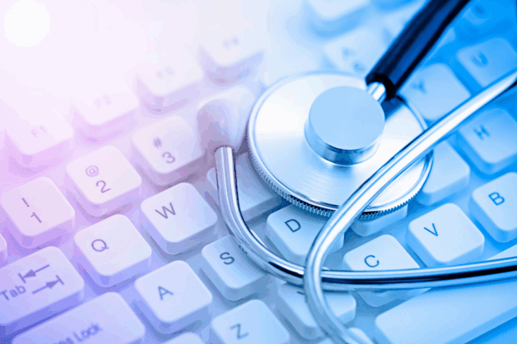 A stethoscope rests on a white computer keyboard, symbolizing the intersection of healthcare and technology.
