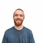 A man with a beard and long hair tied back, wearing a blue t-shirt, smiles at the camera against a plain white background.
