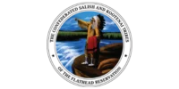 A person wearing a feathered headdress and traditional clothing stands on a rock ledge by a river, pointing toward the horizon—an image echoing the heritage honored by the CSKT Tribal Council, with trees and blue sky in the background.