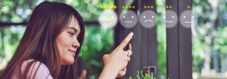 A woman uses her smartphone in a cafe, with five customer satisfaction icons and star ratings displayed in front of her, highlighting the highest rating to show ways to improve customer experience.