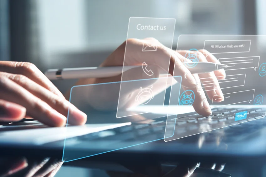 Person typing on a laptop, interacting with virtual chat support and contact icons displayed as digital overlays.