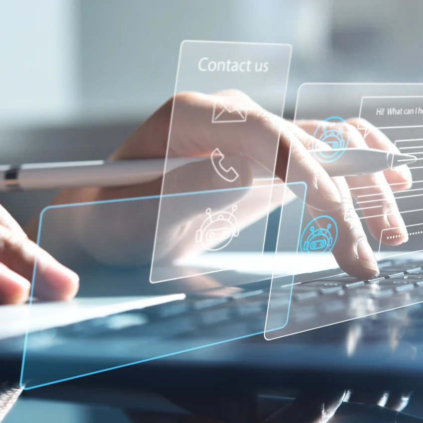 Person typing on a laptop keyboard with virtual interface icons for contact, chatbot, and messaging displayed in the foreground.