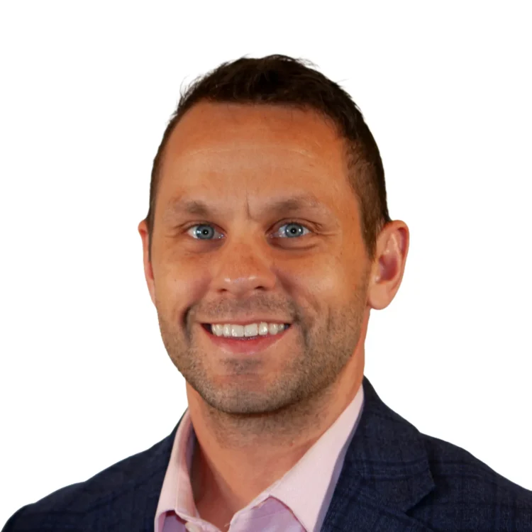 Smiling man in a blue plaid blazer and light pink dress shirt, posing against a plain white background.