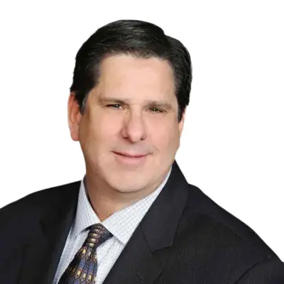 Man in a dark suit and patterned tie poses for a professional headshot against a plain white background.