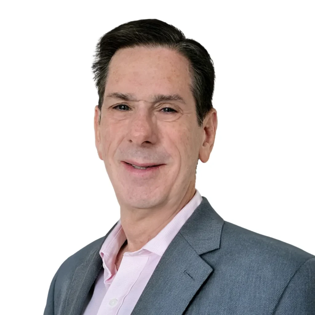 Man wearing a gray blazer and light pink collared shirt, smiling, posed against a plain white background.