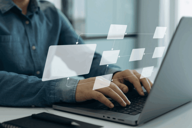 Person typing on a laptop with a transparent digital flowchart diagram overlayed, suggesting workflow or process management.