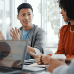 A group of people sit around a table in a bright office, discussing content‑centric intelligent automation with a laptop and notebooks in front of them.