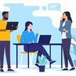 Three people discuss in an office setting; one sits at a desk with a laptop while the other two stand, one holding a laptop. Potted plants decorate the space.