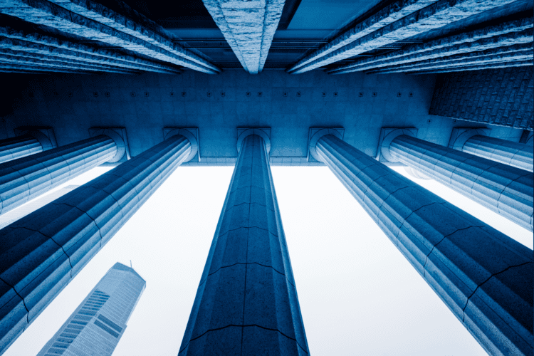 Low-angle view of tall stone columns of a government building, with a modern skyscraper in the background—an inspiring scene for public sector leaders exploring government AI use cases to shape the future.