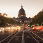 The U.S. Capitol building at dusk with blurred car lights on a street in the foreground and bike lanes visible in the center—a powerful reminder of civic progress that prompts reflection on why government AI projects fail without an effective enterprise knowledge layer to unify efforts.